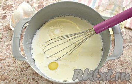 Молоко комнатной температуры вливаем в миску. Вбиваем к нему яйца, вливаем сразу 3 столовых ложки растительного масла, перемешиваем молочно-яичную смесь венчиком.