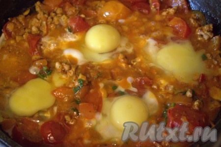 Затем в содержимом сковороды сделать углубления и вбить в них сырые яйца. Присолить яйца.