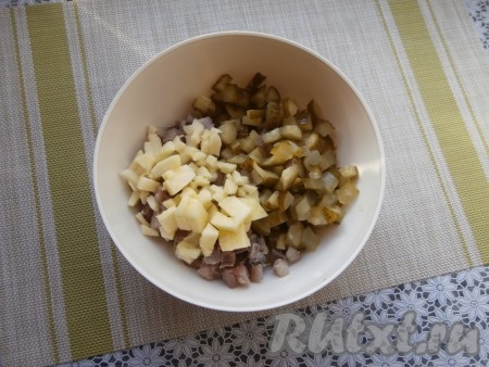 Яблоко очистить от кожицы и семян, нарезать на маленькие кубики. Маринованные огурцы нарезать на средние кубики и вместе с яблоками добавить в салат из картошки и селёдки.