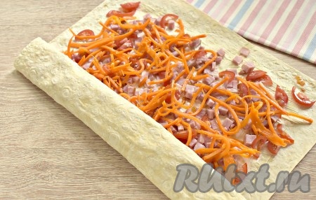 Начиная с узкой стороны, сворачиваем лаваш с начинкой в плотный рулет.