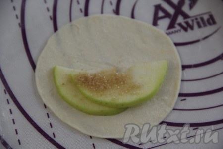 Яблоки вымыть и нарезать на тонкие ломтики. Выложить пару ломтиков яблока на круг из теста так, чтобы половина теста была свободна (как на фото). Присыпать яблоки, примерно, парой щепоток сахара (я использовала тростниковый сахар).