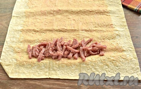 Начинаем собирать шаурму. Выкладываем с одного края половину обжаренной колбасы, оставляя по бокам по 5-7 сантиметров лаваша свободными.