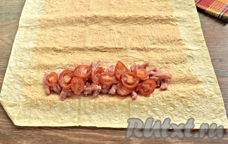 Помидоры черри нарезаем кружками (если используете обычные помидоры, нарежьте их полукружочками). Половину нарезанных помидоров размещаем поверх колбасы.