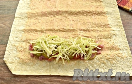 Белокочанную капусту тонко нарезаем, чуть-чуть подсаливаем, перемешиваем, приминая руками. Выкладываем поверх колбасы и овощей половину нашинкованной капусты.