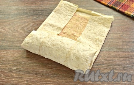 Подгибаем боковые края лаваша к центру и туго сворачиваем шаурму в форме конверта.