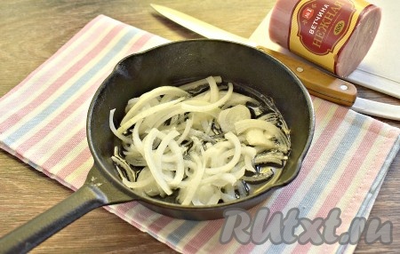 Очищаем репчатый лук, нарезаем его полукольцами и обжариваем в течение 7 минут в разогретом растительном масле на сковороде, периодически перемешивая, на среднем огне. Обжаренный лук остужаем.