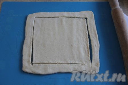 Слегка раскатать слоёное тесто на присыпанной мукой поверхности. Получится квадратный или прямоугольный пласт теста (в зависимости от исходной формы пласта слоёного теста). Внутри теста, отступив 2-3 см от края, сделать разрезы, как на фото (разрезы надо делать с двух противоположенных сторон не до конца, чтобы образовались как бы две буквы "Г").