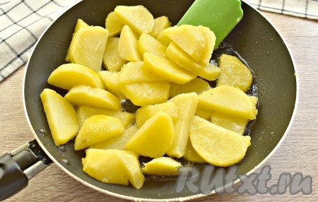 Нарезанный картофель выкладываем на сковороду, разогретую с растительным маслом, и обжариваем его на среднем огне до образования лёгкой румяной корочки со всех сторон, пару раз перемешиваем.