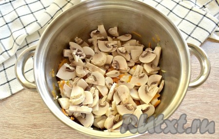 Свежие шампиньоны промываем, нарезаем пластинками и выкладываем к кусочкам курицы, обжаренным с овощами, перемешиваем. Грибы с куриным мясом обжариваем, иногда помешивая, минут 5.