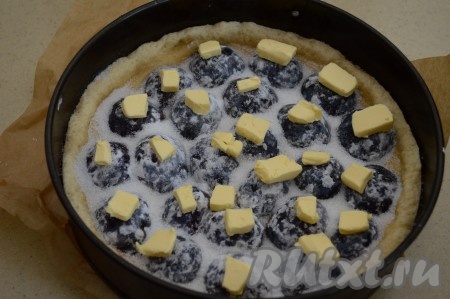 Сливы сверху посыпать сахаром и равномерно разложить нарезанное на небольшие кусочки сливочное масло (я выкладывала масло поверх слив).