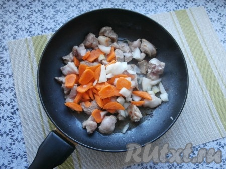 Обжарить свинину на среднем огне до изменения цвета со всех сторон, затем добавить нарезанные крупно лук и морковь, перемешать и обжаривать овощи с мясом минут 4-5, иногда помешивая.