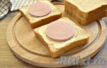 На каждый смазанный кусок хлеба кладём по кружочку колбасы.