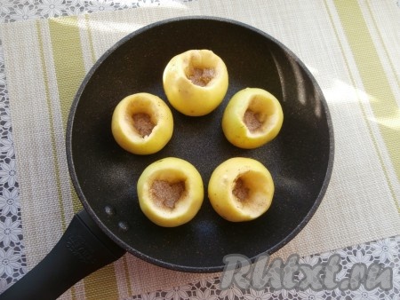 Половину смеси сахара и корицы равномерно разложить в углубления яблок.