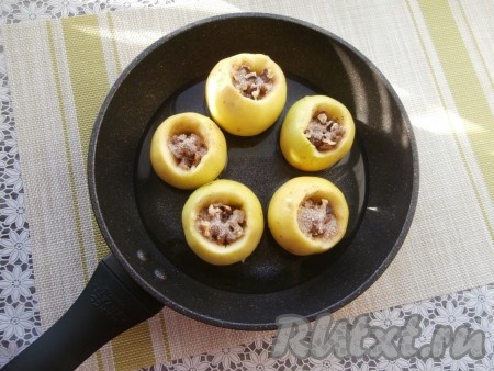 Оставшуюся смесь сахара и корицы равномерно распределить между яблоками, засыпая в углубления. В сковороду налить воду.