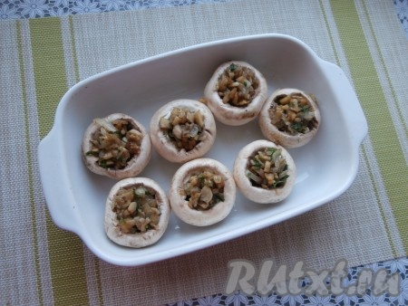 Далее шляпки шампиньонов наполнить слегка остывшими обжаренными ножками грибов с луком. Поместить фаршированные шляпки грибов в форму для запекания.