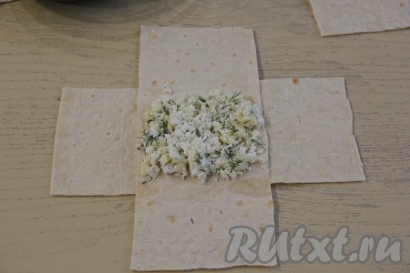 На середину двух полосок лаваша, положенные крест-накрест, выложить 1,5-2 столовых ложки творожно-сырной начинки, разровнять, как на фото.