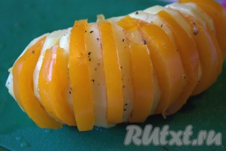 В каждую прорезь картошки-гармошки поместить по полукружочку помидора. В отдельной ёмкости соединить растительное масло и пропущенные через пресс зубчики чеснока, тщательно перемешать и получившимся чесночным маслом смазать снаружи с помощью силиконовой кисточки картофелины с помидорами.