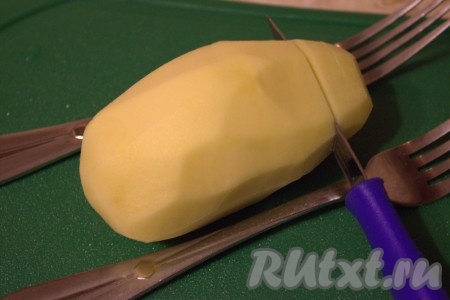 Картошку вымыть и очистить от кожуры. На картофеле сделать поперечные надрезы на расстоянии 1-1,5 сантиметра, немного не дорезая до нижнего края клубня. Я для этого кладу две вилки по бокам картошки, они не дают ножу прорезать клубень до конца. Получается что-то отдалённо напоминающее веер или гармошку.