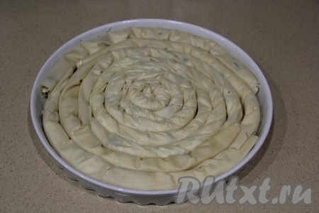 Форму для выпечки (я взяла форму диаметром 28 см) смазать маслом. Выложить сформированные рулетики в форму в виде улитки (то есть рулетики, начиная с центра формы, нужно выкладывать один за другим по кругу). 