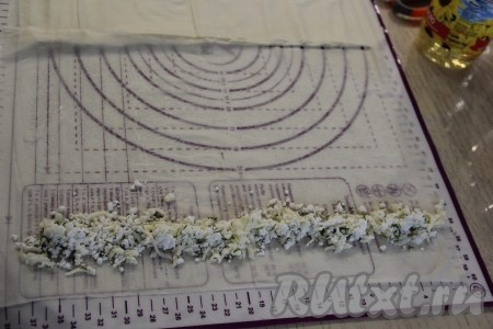 На силиконовом коврике расстелить лист теста фило, смазать его маслом (я смазывала растительным маслом, можно смазать и растопленным сливочным маслом). Тесто фило очень любит масло, поэтому масла не жалеем. Я смазывала руками. Немного отступив от края теста, выложить часть творожно-сырной начинки в виде длинной полоски, как на фото.