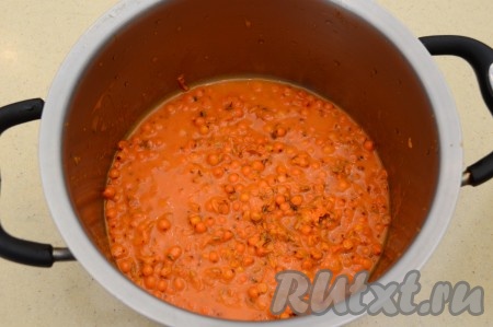 Всыпать облепиху в кастрюлю подходящего размера. Размять толкушкой, чтобы выделился сок. Все ягодки разминать не нужно.