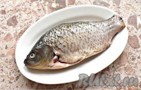 Карася очищаем от чешуи и потрошим, убирая внутренности и чёрную плёнку из брюшка. Я использовала замороженного карася. Рыбка была заранее очищена, поэтому я только ее разморозила. Срезаем плавники и хвост. С каждой стороны карася острым ножом делаем небольшие надрезы возле хребта. Эти разрезы помогут рыбке равномернее запечься.