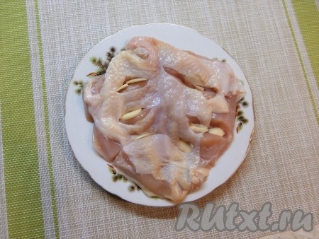 Чеснок очистить от кожуры и нарезать на достаточно толстые пластины. Куриную грудку отделить от кости, сохраняя кожу. Куриную грудку без кости посолить и нашпиговать пластинами чеснока, сделав несколько надрезов острым ножом сверху.