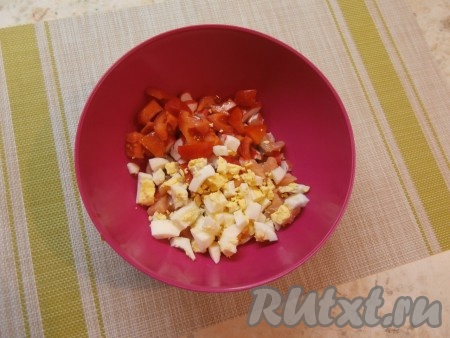 Крабовые палочки тоже нарезать на средние кусочки, выложить к курице. Далее добавить свежий помидор, нарезанный на средние кубики, и рубленое варёное яйцо.