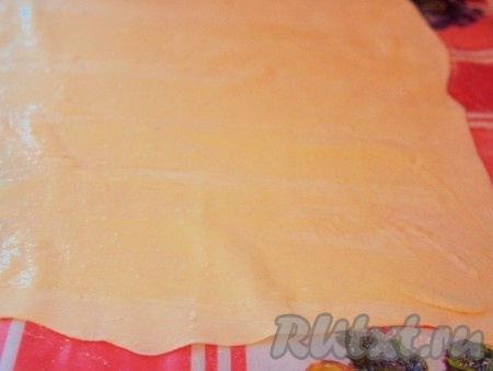 Половину теста тонко раскатать, смазать яйцом.