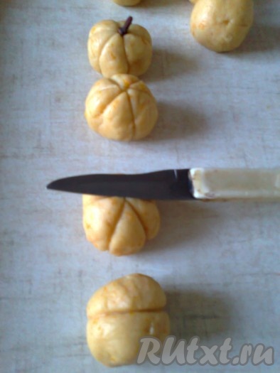 Тупой стороной лезвия ножа придать каждому шарику из теста форму тыквы (для этого сначала сделать полоску по середине шарика, а затем на каждой стороне ещё три полоски от центра вниз).