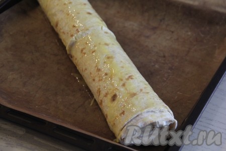 Выложить штрудель на противень, застеленный пергаментом (или тефлоновым ковриком). Смазать поверхность штруделя слегка взбитым желтком.