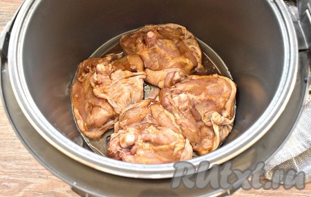 Вливаем растительное масло в съёмную чашу мультиварки, выкладываем куриные бёдра, замаринованные в соевом соусе.