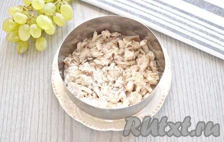 Куриное мясо (я взяла куриное филе, можно взять филе бедра) отварить в подсоленной воде в течение 30 минут с момента закипания воды. Отварить яйца вкрутую (на отваривание с момента начала кипения воды потребуется минут 8-10), а затем остудить их в ледяной воде и очистить. Для сборки блюда я использовала сервировочное кольцо, поставив его на плоскую тарелку, но подойдёт и прозрачный салатник. Итак, остывшее куриное мясо нарезаем на мелкие кусочки и выкладываем первым слоем.