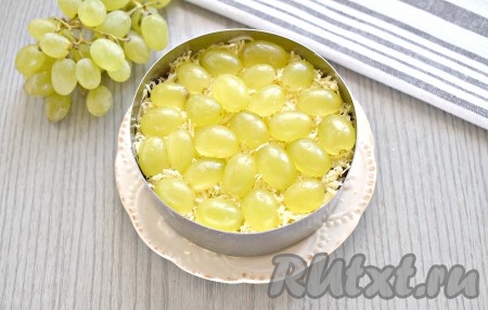Промываем виноград. Разрезаем каждую виноградинку на две половинки. Если есть косточки, то обязательно удаляем их. Украшаем салат сверху виноградом и отправляем его настаиваться в холодильник, как минимум, на 30 минут.