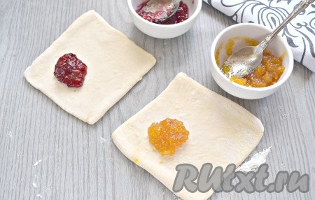 На одну сторону квадратных заготовок выкладываем по чайной ложке любимого варенья.

