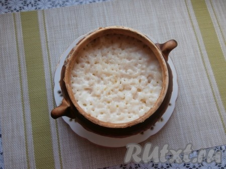 Горшочек накрыть крышкой и поместить его в холодную духовку. Под горшочек обязательно поставьте какую-либо ёмкость на всякий случай - немного молока может вытечь. Выставить температуру 130-140 градусов на 15 минут. Затем температуру увеличить до 180 градусов и томить молочную рисовую кашу в духовке ещё 1,5-2 часа. Проверять готовность нужно по рису.