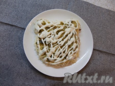 Следующим слоем нужно выложить маринованный огурчик, нарезанный на небольшие кубики, смазать майонезом.