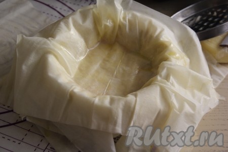 Накрыть начинку тремя листами теста фило, каждый из которых предварительно смазать маслом. Края листов должны свисать с бортов формы.