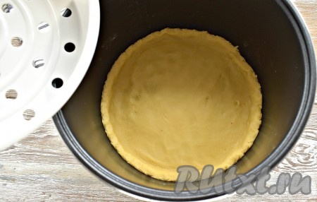 Большую часть теста раскатываем в круглый пласт по размеру дна чаши мультиварки. Я для удобства, чтобы не ошибиться с размером, использовала в качестве «трафарета» поддон для приготовления на пару (он идёт в комплекте с мультиваркой). Пласт выкладываем в чашу, смазывать её необязательно. Делаем невысокие бортики (высотой, примерно, 1,5-2 см).