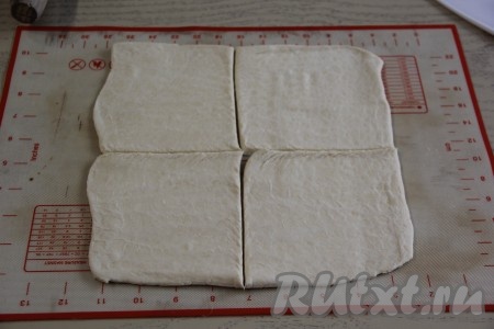 После того как начинка остынет и тесто разморозится, можно приступать к формированию конвертиков. Вначале слегка раскатать на силиконовом коврике (или на другой поверхности, припылённой мукой) первый пласт теста и разрезать его на 4 квадрата. Аналогично раскатать и нарезать второй пласт теста. Получатся 8 квадратов слоёного теста.