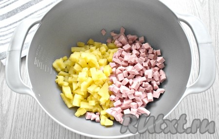 Отвариваем накануне картофель, морковь, яйца. Яйца варим вкрутую (минут 9-10 после закипания). Картофель и морковь отвариваем до мягкости (20-30 минут после закипания). Картошку варим в кожуре, следим чтобы она не разварилась. Морковку тоже можно сварить в кожуре. Варёные овощи и яйца остужаем, а затем очищаем. Картофель и колбасу нарезаем на мелкие кубики и выкладываем в миску.