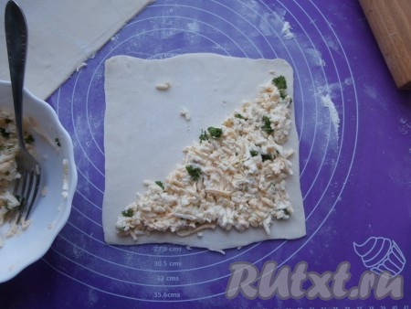 На одну половину раскатанного квадрата выложить половину сырной массы, не доходя до самых краёв (как на фото).
