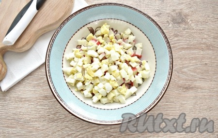 Яйца тоже нарезаем на небольшие кубики (нарезать можно специальной яйцерезкой или ножом), выкладываем к крабовым палочкам.