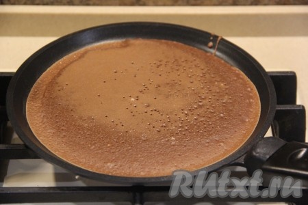Хорошо раскалить сковороду. Перед выпечкой первого блинчика, можно немного смазать сковороду маслом. Я маслом сковороду не смазывала, но тут всё зависит от вашей блинной сковороды. На раскалённую сковороду налить половник шоколадного теста, равномерно распределяя его по дну сковородки, и выпекать блинчик на среднем огне с двух сторон. Затем переложить на тарелку, а оставшееся тесто перемешать и постепенно пожарить все шоколадные блинчики, складывая их на тарелку.