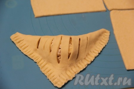 Частью теста с разрезами накрыть часть теста, на которую выложена начинка, получится треугольная слойка. Хорошо скрепить края теста, это удобно делать вилкой. Аналогично сформировать все слойки.