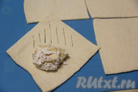 Каждый квадрат теста визуально поделить по диагонали на две части. Выложить на одну часть теста 1 столовую ложку с горкой начинки, а на другом крае квадрата сделать несколько разрезов ножом (как на фото).