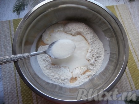 Влить оставшиеся 150 миллилитров кефира в отдельную ёмкость, добавить соду, сразу перемешать и оставить на 5 минут. Кефир, благодаря соде, станет пышным, с пузырьками. Затем, подливая смесь кефира и соды в миску с мучной смесью, замешивать тесто сначала ложкой.