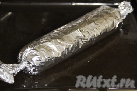 Завернуть рулет в фольгу, скрутить фольгу с двух краёв рулета, как конфету, а затем переложить на противень.