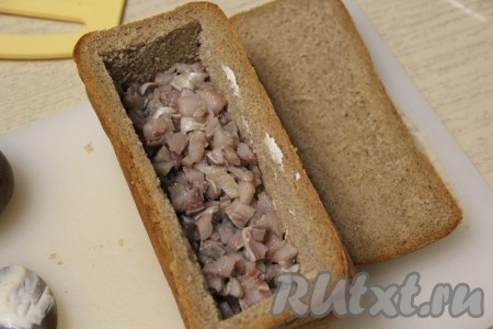 Из филе сельди удалить косточки, если они есть, а затем мелко нарезать и выложить следующим слоем. 