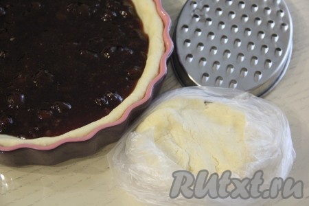 По прошествии 30 минут достать форму с тестом из холодильника. На тесто равномерно выложить варенье. Затем достать кусочек творожного теста из морозилки и натереть его на крупной тёрке, равномерно покрывая варенье. Поставить форму в разогретую духовку и выпекать пирог минут 45 при температуре 200 градусов.